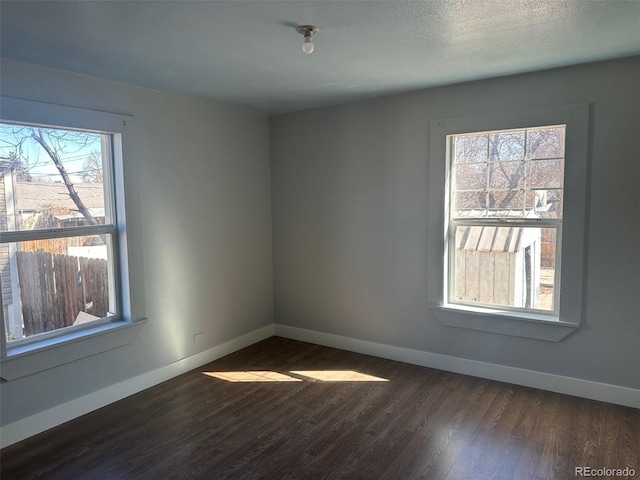 empty room with baseboards and dark wood-type flooring