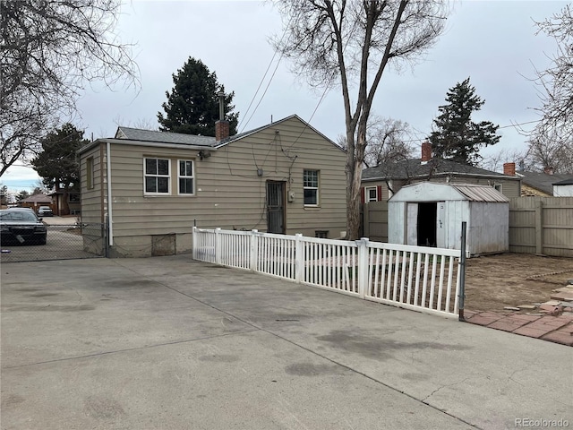 rear view of property with a chimney, an outdoor structure, a patio area, fence private yard, and a storage unit
