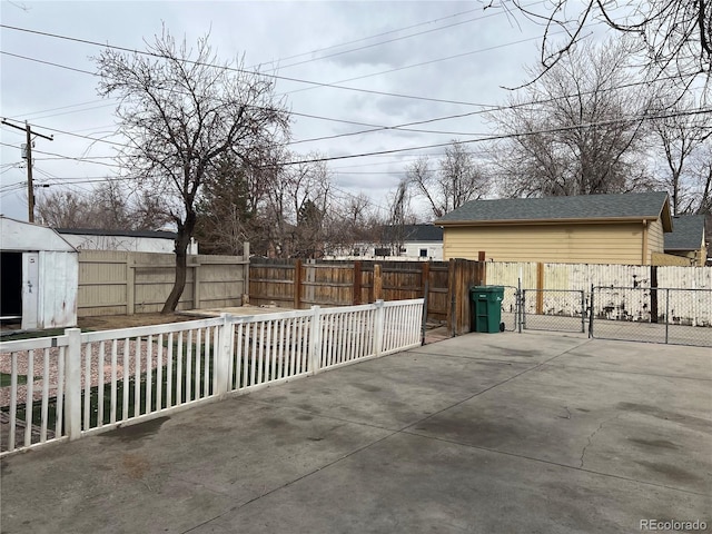 view of patio / terrace featuring an outbuilding, a gate, a fenced backyard, and a shed