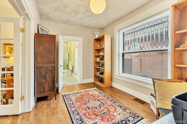 living area featuring crown molding and light wood-type flooring