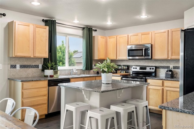 4626 Dancing Rain Way, Colorado Springs, CO 80911 - kitchen with appliances with stainless steel finishes, light brown cabinets, a breakfast bar, dark wood-style floors, and recessed lighting
