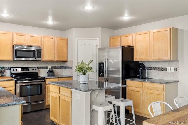 4626 Dancing Rain Way, Colorado Springs, CO 80911 - kitchen featuring stainless steel appliances, light brown cabinetry, backsplash, a kitchen breakfast bar, and recessed lighting