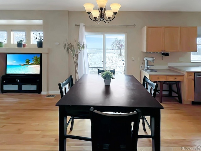 dining room with light wood-type flooring and an inviting chandelier