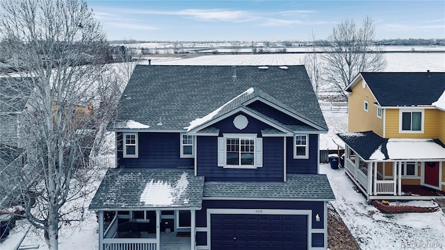 traditional-style house featuring covered porch, a shingled roof, and an attached garage