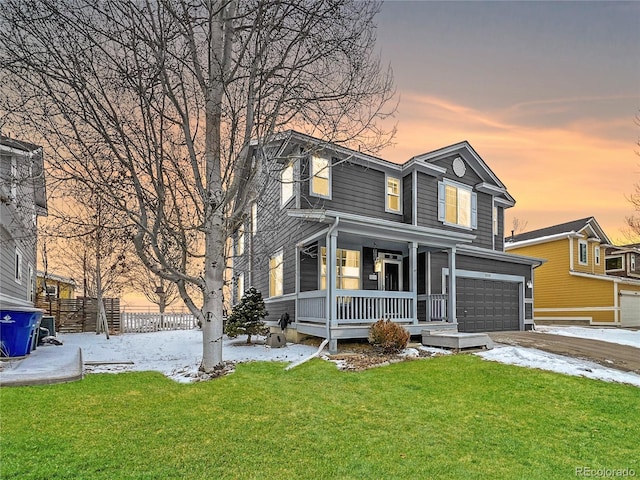 traditional-style home with fence, a yard, covered porch, concrete driveway, and a garage