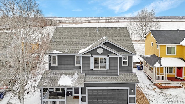 view of front of house featuring covered porch, a garage, and a shingled roof