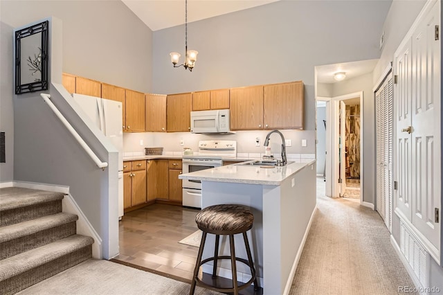 kitchen featuring white appliances, high vaulted ceiling, light countertops, a chandelier, and a sink