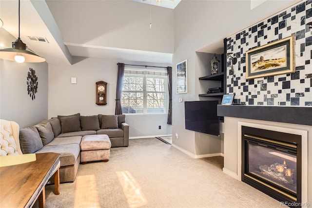 carpeted living area with baseboards, visible vents, and a glass covered fireplace