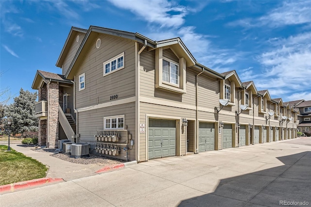 view of home's exterior with a residential view, central AC unit, and community garages