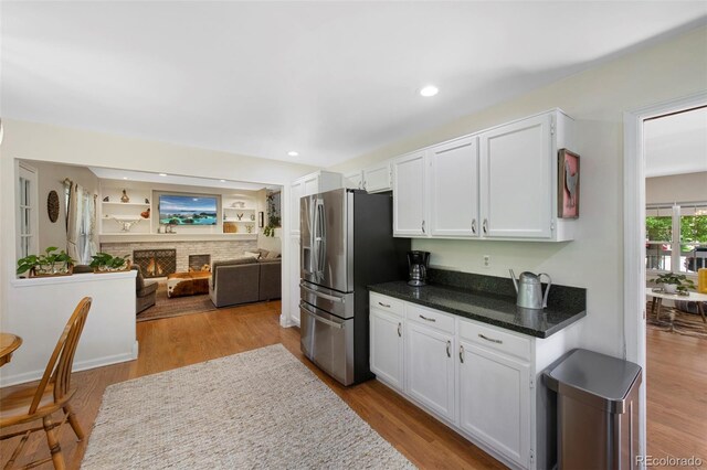 7773 Gunsight Pass, Littleton, CO 80127 - kitchen featuring stainless steel refrigerator with ice dispenser, white cabinets, open floor plan, wood finished floors, and recessed lighting