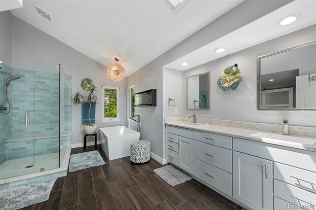7773 Gunsight Pass, Littleton, CO 80127 - full bath with lofted ceiling, double vanity, a stall shower, a soaking tub, and baseboards