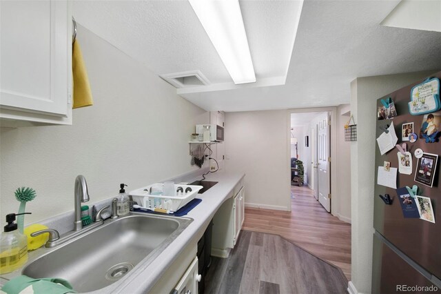 7773 Gunsight Pass, Littleton, CO 80127 - kitchen featuring a sink, wood finished floors, freestanding refrigerator, white cabinetry, and a textured ceiling