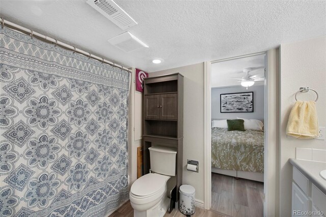 7773 Gunsight Pass, Littleton, CO 80127 - bathroom featuring a textured ceiling, connected bathroom, wood finished floors, vanity, and toilet