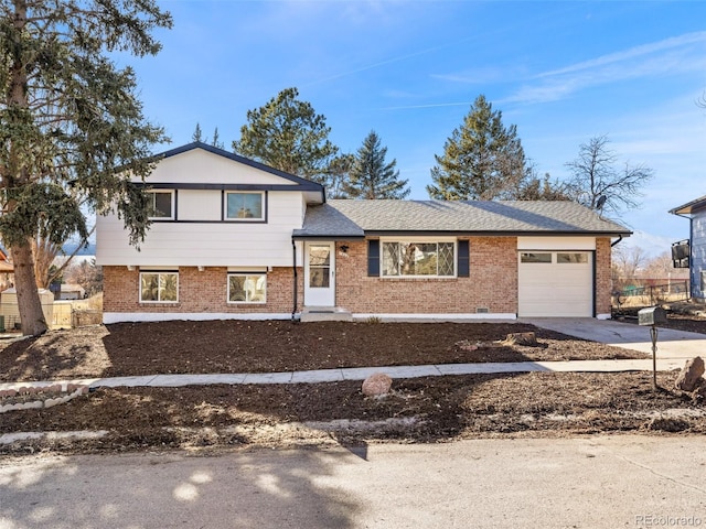 split level home with brick siding, driveway, a garage, and roof with shingles