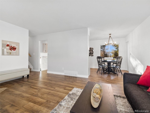 living room with visible vents, baseboards, stairway, hardwood / wood-style floors, and a notable chandelier