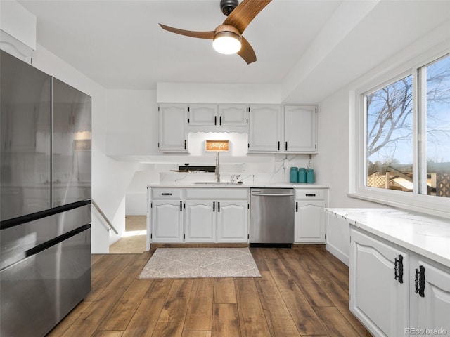 kitchen featuring a ceiling fan, a sink, stainless steel appliances, dark wood-type flooring, and white cabinetry