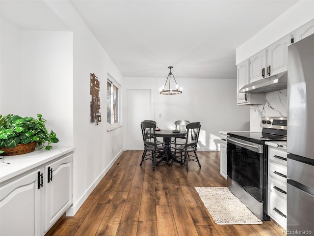 kitchen featuring backsplash, under cabinet range hood, dark wood finished floors, light countertops, and appliances with stainless steel finishes