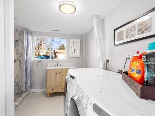 laundry area featuring washing machine and clothes dryer, visible vents, baseboards, laundry area, and a sink