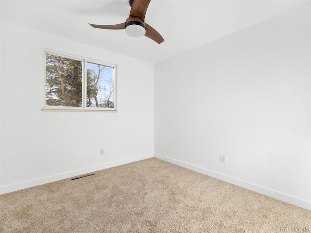 carpeted empty room featuring visible vents, a ceiling fan, and baseboards