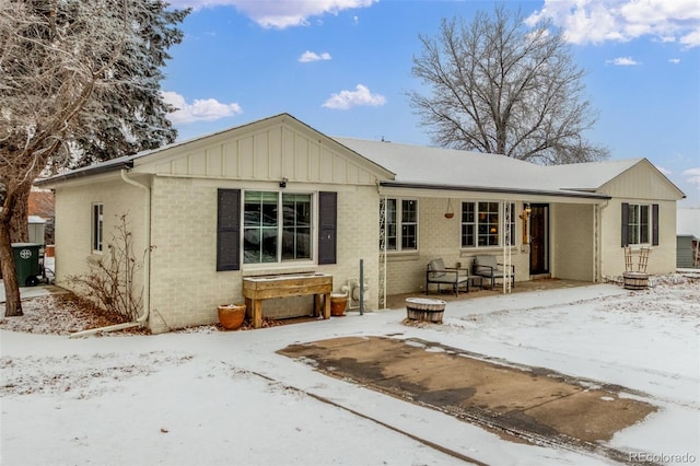 snow covered back of property featuring brick siding