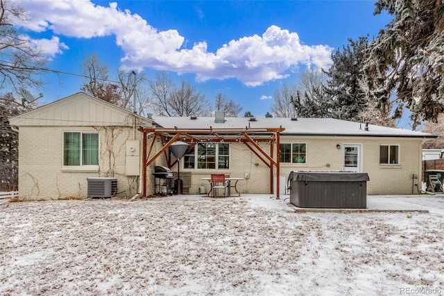 3865 Independence Ct, Wheat Ridge, CO 80033 - snow covered rear of property featuring a patio, a hot tub, central AC, and brick siding
