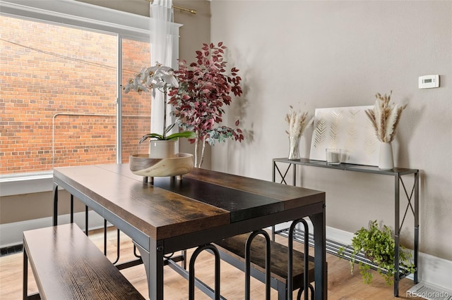 dining space with brick wall and light hardwood / wood-style flooring