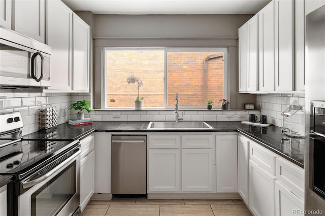 kitchen featuring appliances with stainless steel finishes, sink, white cabinets, and backsplash