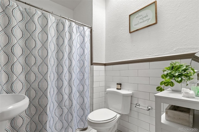 bathroom with tile walls, a shower with shower curtain, and toilet