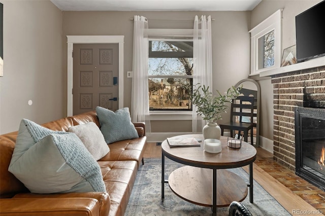 living room featuring a brick fireplace and wood finished floors