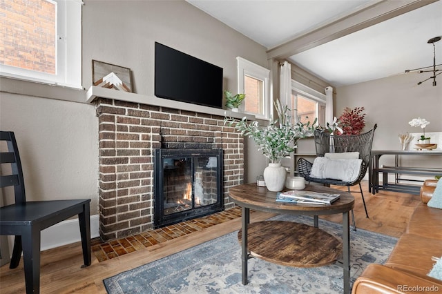 living room featuring beam ceiling, wood finished floors, and a fireplace