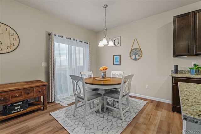 dining space featuring baseboards, light wood finished floors, and an inviting chandelier