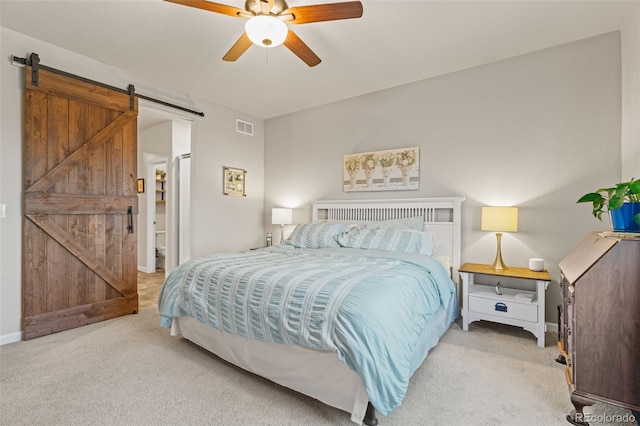 carpeted bedroom with ceiling fan, a barn door, visible vents, and baseboards