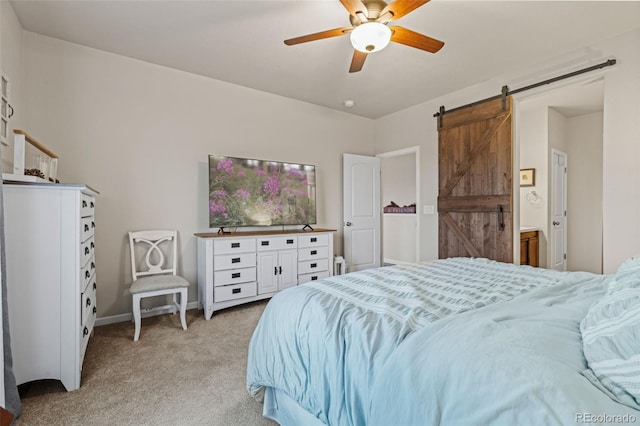 bedroom with ensuite bathroom, a ceiling fan, a barn door, light carpet, and baseboards