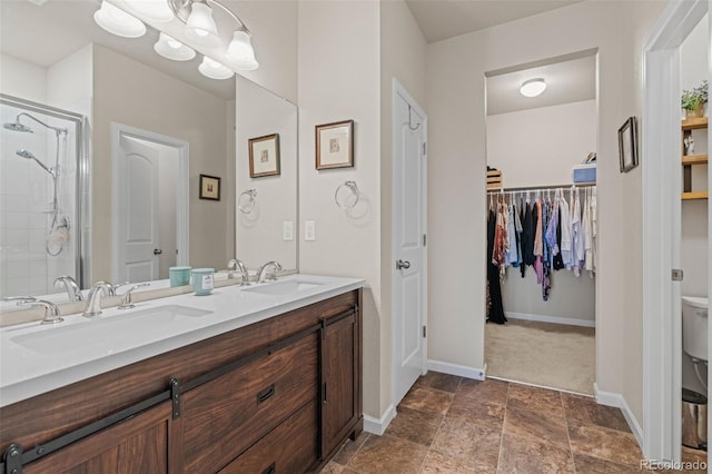 full bathroom featuring baseboards, double vanity, a sink, and a shower stall