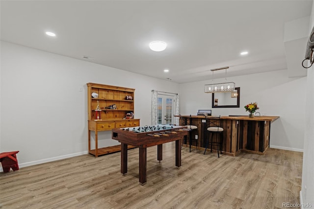 recreation room with a bar, wood finished floors, and baseboards