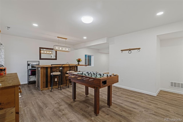 rec room featuring baseboards, visible vents, indoor bar, and wood finished floors