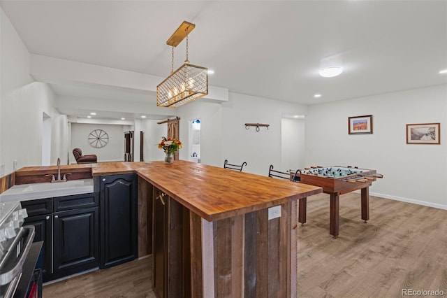 kitchen featuring decorative light fixtures, stainless steel range, wooden counters, a sink, and wood finished floors