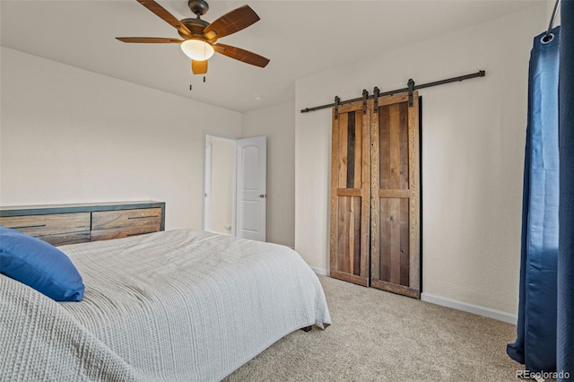 bedroom with a barn door, carpet flooring, a ceiling fan, and baseboards