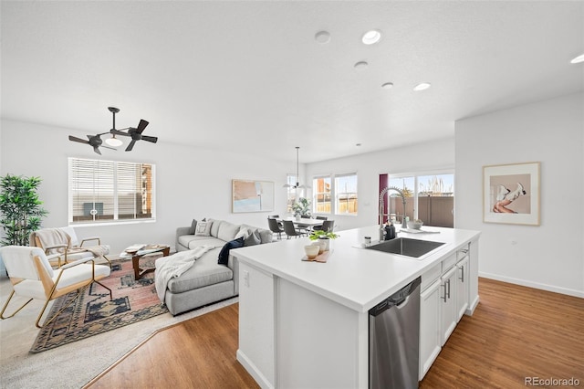 kitchen featuring sink, light hardwood / wood-style floors, white cabinets, a center island with sink, and stainless steel dishwasher