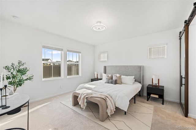 bedroom featuring light carpet and a barn door