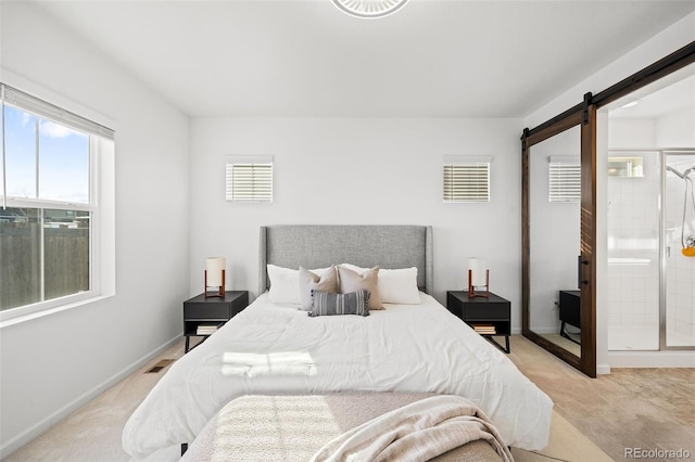 bedroom featuring ensuite bathroom, a barn door, and light colored carpet