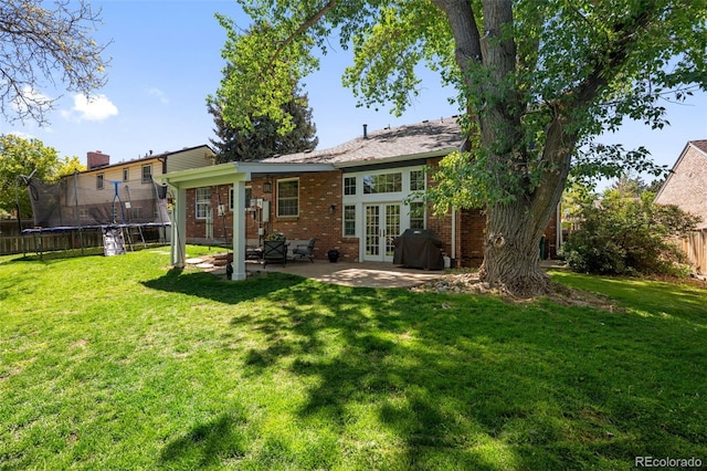3767 E Phillips Cir, Centennial, CO 80122 - back of property with french doors, a trampoline, a patio, and brick siding