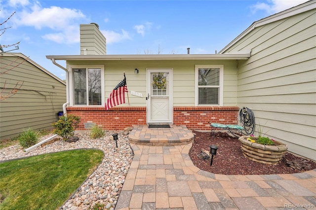 property entrance with brick siding and a chimney