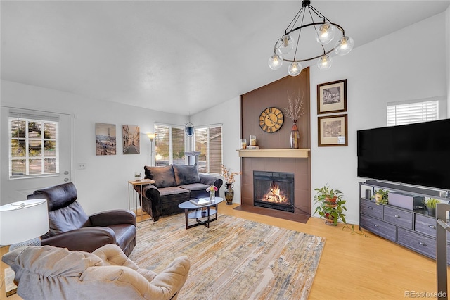 living room featuring a tile fireplace, wood finished floors, and lofted ceiling