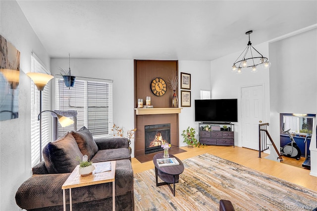 living room with wood finished floors, a chandelier, and a fireplace