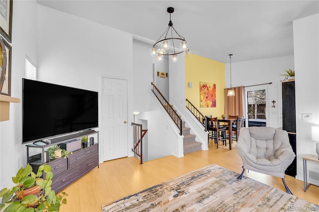 living room with a chandelier, wood finished floors, stairway, and a towering ceiling