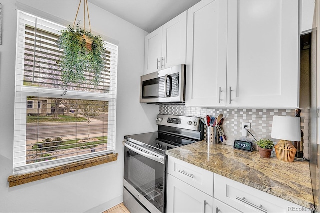 kitchen with stainless steel appliances, backsplash, white cabinets, and light stone counters