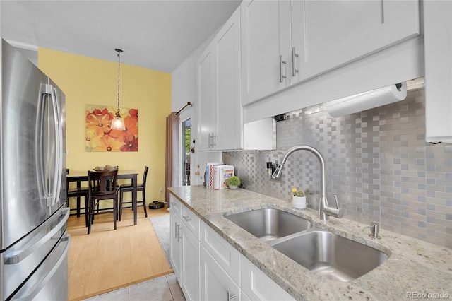 kitchen featuring freestanding refrigerator, a sink, white cabinets, and tasteful backsplash