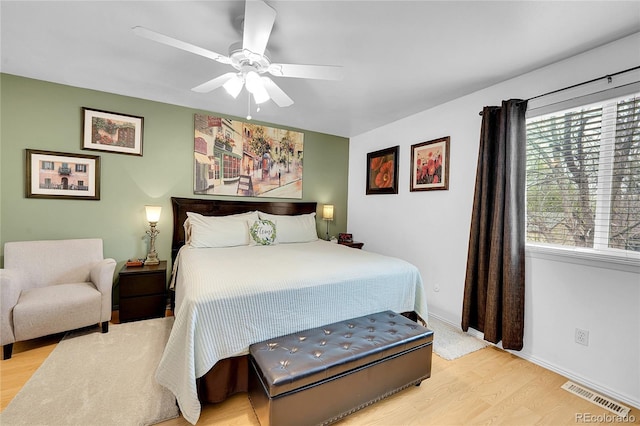 bedroom with multiple windows, wood finished floors, a ceiling fan, and baseboards