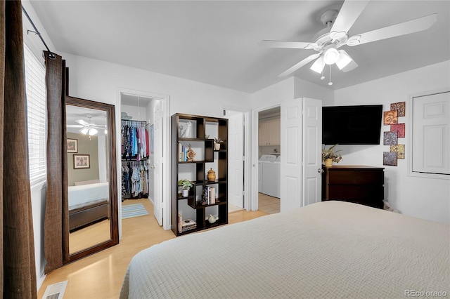 bedroom with washer / clothes dryer, a spacious closet, ensuite bathroom, a closet, and a ceiling fan